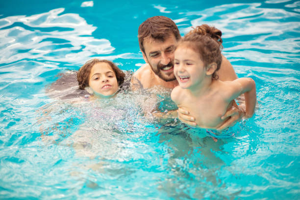 istock Father with kids playing in the pool. 1319725781