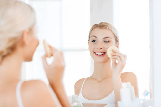 istock young woman washing face with sponge at bathroom 1319728186