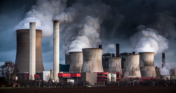 Chimneys and cooling towers from a coal fired power station releasing smoke and steam into the atmosphere. The power plant is also releasing CO2 which contributes to global warming and climate change.