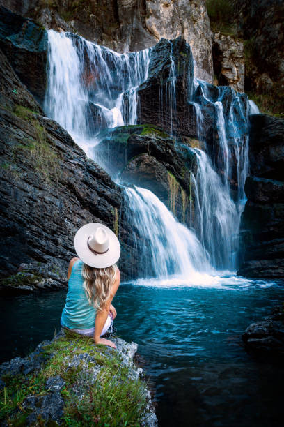 Female sitting by waterfall in snowy mountains