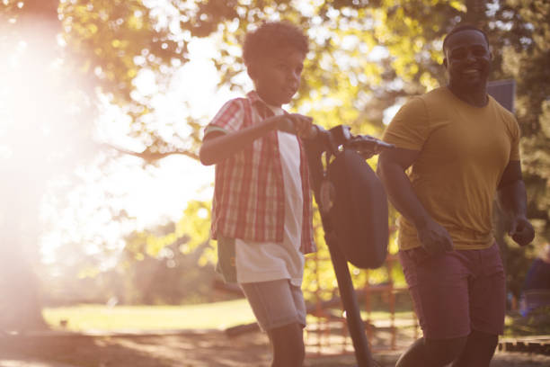 istock African American father having fun outdoors with his son. Little boy riding scooter. 1319737580