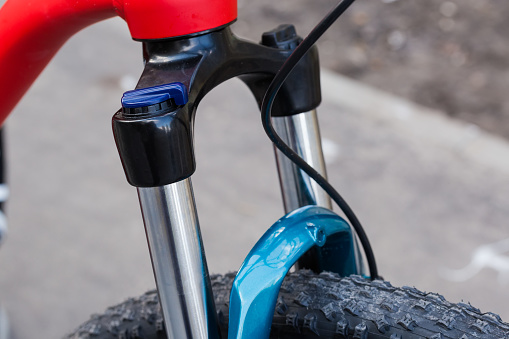 Fragment of head tube, top part of fork with shock absorbers of modern bicycle, close-up in selective focus