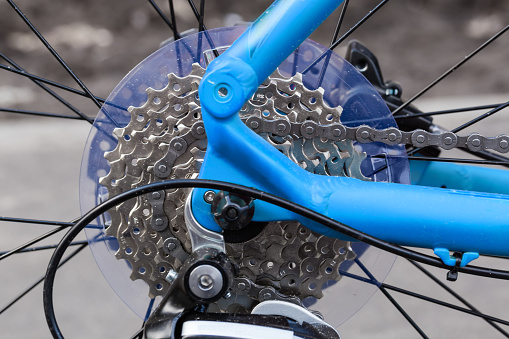 Fragment of rear wheel and frame of modern bicycle with set of sprockets, close-up in selective focus