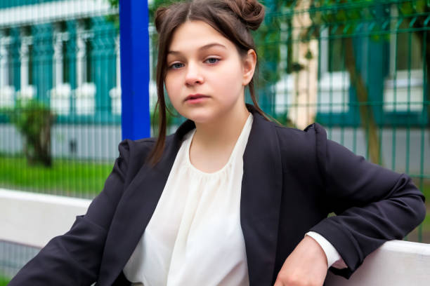 Portrait of thirteen-year-old schoolgirl in white blouse, plaid skirt and jacket at schoo Art noise film style image. Portrait of thirteen-year-old schoolgirl in white blouse, plaid skirt and jacket at school. Emotional teen girl posing looking at camera. Concept of school age and learning back to schoo stock pictures, royalty-free photos & images