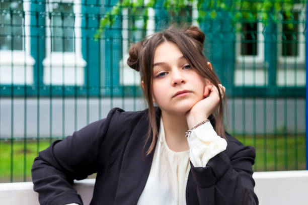 Portrait of thirteen-year-old schoolgirl in white blouse, plaid skirt and jacket at schoo Art noise film style image. Portrait of thirteen-year-old schoolgirl in white blouse, plaid skirt and jacket at school. Emotional teen girl posing looking at camera. Concept of school age and learning back to schoo stock pictures, royalty-free photos & images
