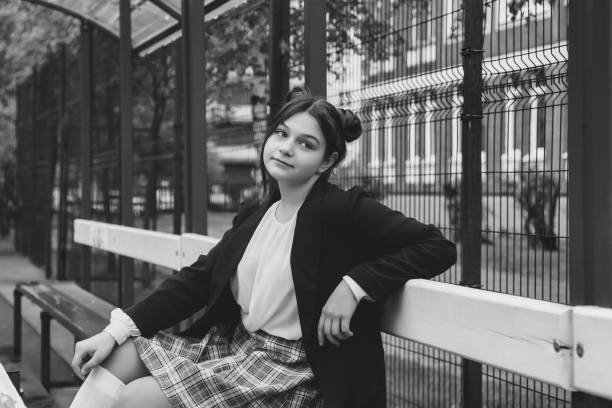 Portrait of thirteen-year-old schoolgirl in white blouse, plaid skirt and jacket at schoo Art noise film style image. Portrait of thirteen-year-old schoolgirl in white blouse, plaid skirt and jacket at school. Emotional teen girl posing looking at camera. Concept of school age and learning back to schoo stock pictures, royalty-free photos & images