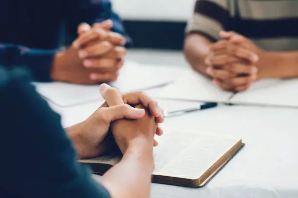 Photo of group of christian are congregants join hands to pray and seek the blessings of God, They were reading the Bible and sharing the gospel with copy space. prayer meeting concept.