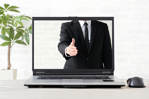 PC with screen of business man trying to shake hands