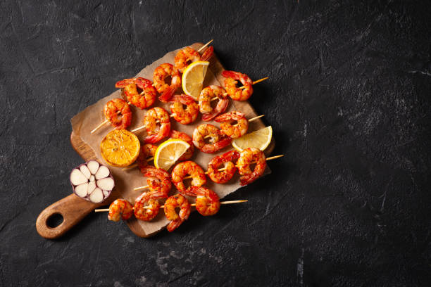 istock Grilled shrimp with garlic and lemon on black background 1319748671