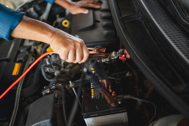 el mecánico del coche utiliza un cable de puente de batería para cargar la batería muerta. concepto de servicio de reparación de coches. - cable car fotografías e imágenes de stock