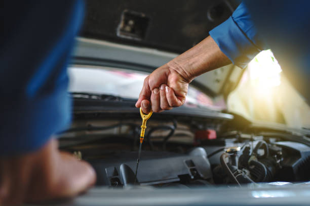 primer plano de la mano de un mecánico asiático. el mecánico automático está revisando el aceite del motor en un vehículo en el garaje. concepto de mantenimiento. - aceite de motor fotografías e imágenes de stock