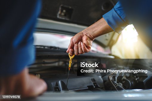 istock Close up of the hand of an asian mechanic. Auto mechanic is checking the engine oil in a vehicle at the garage. Maintenance concept. 1319749078