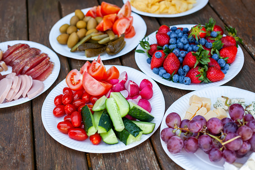 Variety of healthy party food and snacks on paper plates  - fruits, vegetables and cheese