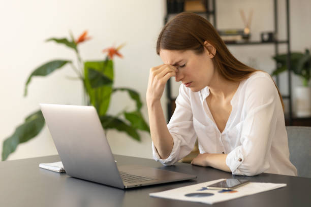 istock Frustrated millennial caucasian freelancer woman overworked by computer feel headache migraine sitting at work table with laptop. Chronic fatigue concept 1319755506