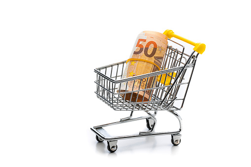Wire shopping cart with rolled 50 Euro paper currency inside isolated on white background