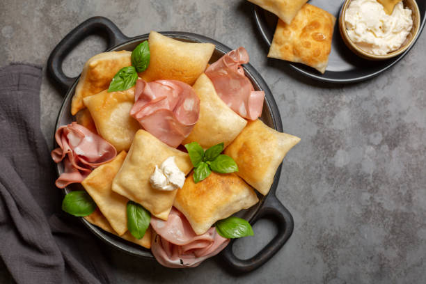 top-ansicht der italienischen vorspeise. gebratenes brot crescentine oder gnocco fritto mit mortadella und weichkäse, verziert mit basilikumblättern. traditionelles essen. - gnocco fritto stock-fotos und bilder