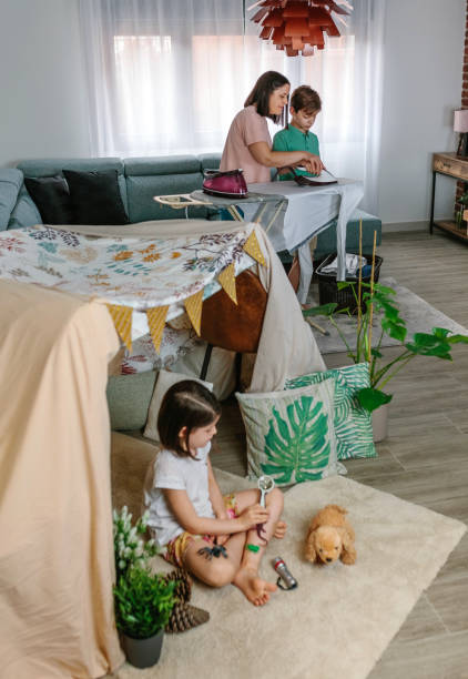 어머니는 그녀의 딸이 집에서 캠핑을 하는 동안 철에 그녀의 십대 아들을 가르치고 - home interior male little girls iron 뉴스 사진 이미지