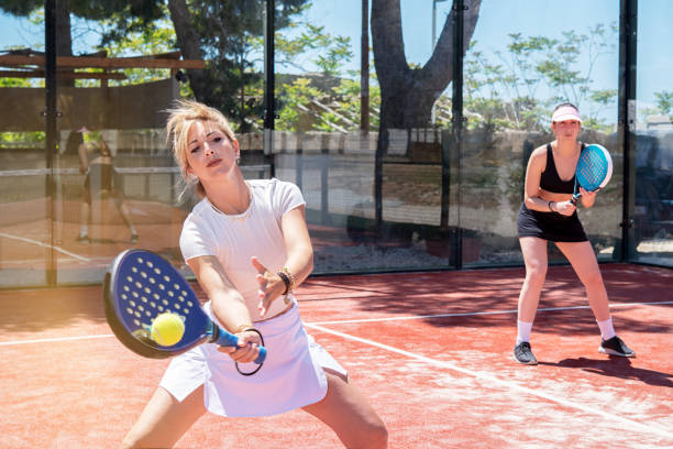 woman smashing in paddle tennis action. Training Basket balls in foreground stock photo