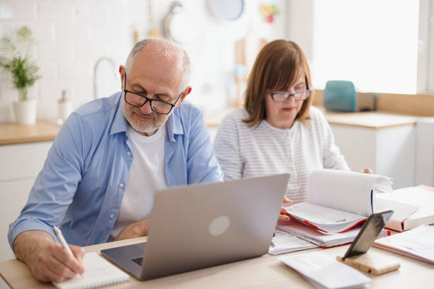 istock Senior couple sitting at kitchen table doing taxes and paying utility bils 1319759493