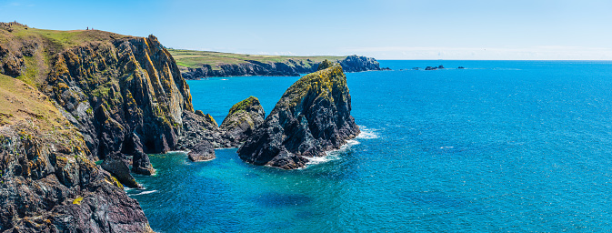 The dramatic sea stacks and rocky cliffs overlooking the turquoise ocean and idyllic sandy beaches of Kynance Cove, Cornwall, UK.