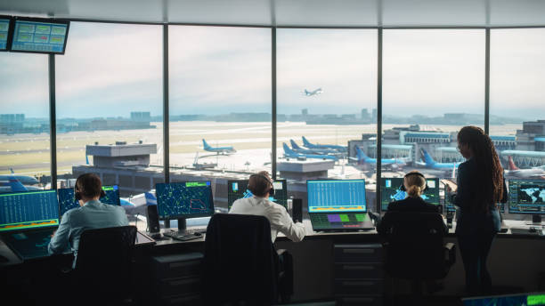 Diverse Air Traffic Control Team Working in a Modern Airport Tower. Office Room is Full of Desktop Computer Displays with Navigation Screens, Airplane Departure and Arrival Data for Controllers. equipo diverso de control de tráfico aéreo trabajando en una torre moderna del aeropuerto. la sala de oficina está llena de pantallas de computadoras de escritorio con pantallas de navegación, datos de salida y llegada de aviones para los controladores