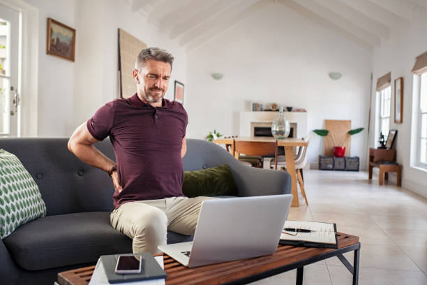 reifer mann, der sich zurückst, während er zu hause arbeitet - posture stock-fotos und bilder