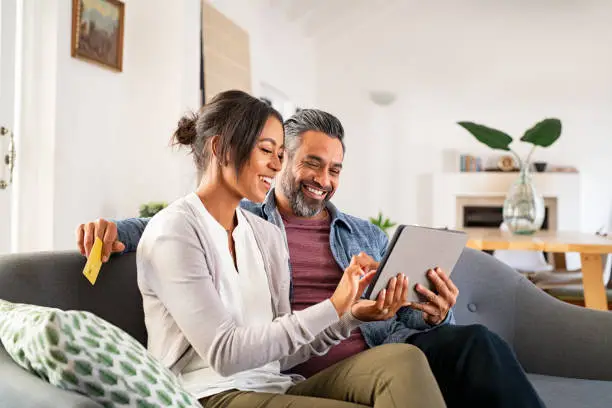 Photo of Multiethnic mid adult couple using digital tablet at home