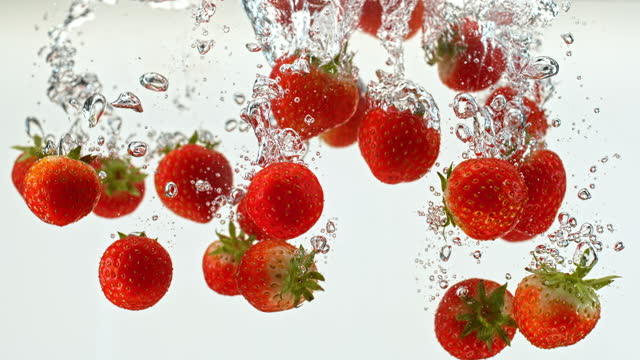 SLO MO LD Strawberries falling into the water