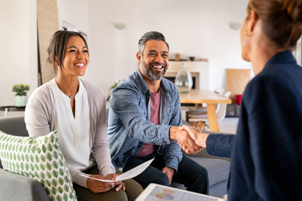 Multiethnic couple handshake with consultant at home Mature indian man shaking hands with financial advisor at home. Happy smiling couple greeting broker with handshake at home. Multiethnic mid adult man and hispanic woman sealing a contract. mortgage stock pictures, royalty-free photos & images