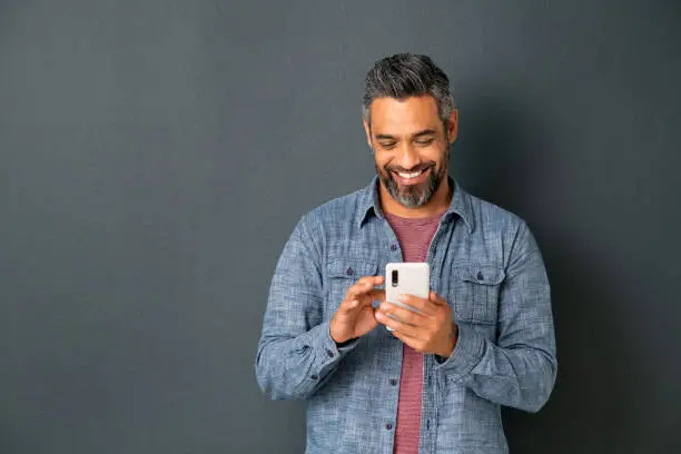 Photo of Mature indian man messaging on smartphone