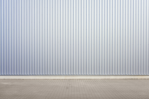 Pared exterior de almacén de chapa corrugada de aluminio y carretera pavimentada en zona exterior como imagen de fondo. photo