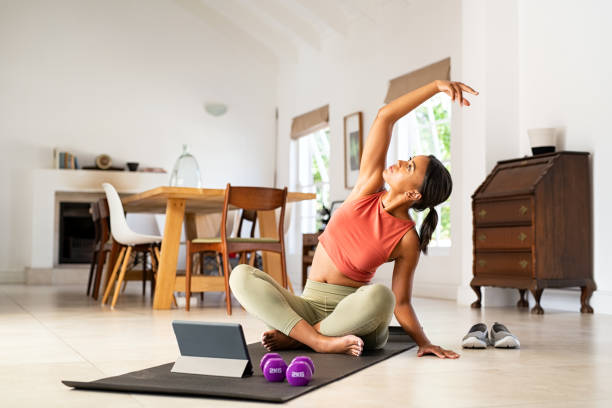 mujer adulta mediana practicando ejercicio de estiramiento en casa - women yoga yoga class mature adult fotografías e imágenes de stock