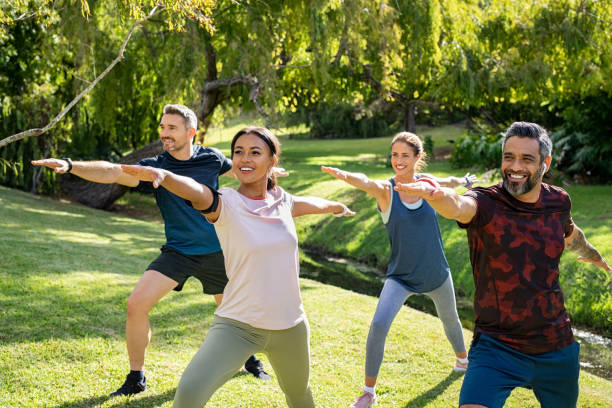 gruppe von reifen männern und frauen, die sich nach dem training im park strecken - yoga exercising outdoors group of people stock-fotos und bilder