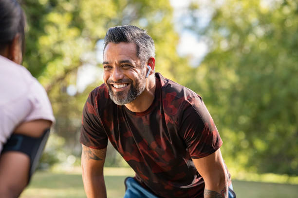 maturo uomo di razza mista che si prende una pausa dopo aver fatto jogging con la sua ragazza - african ethnicity exercising muscular build healthy lifestyle foto e immagini stock