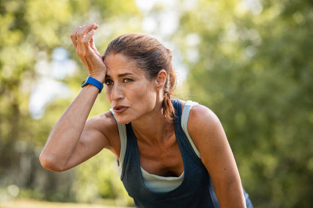 müde reife läufer wischen schweiß nach dem training im park - women sweat healthy lifestyle exercising stock-fotos und bilder