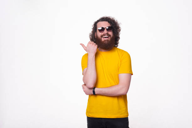 istock Cheerful young man with beard pointing away over white background 1319764928