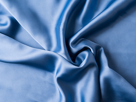 Indigo blue satin texture flowing fabric background with waves and crease