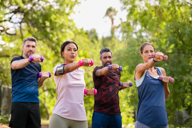 Photo of Multiethnic mature people exercising in park with dumbbells at park