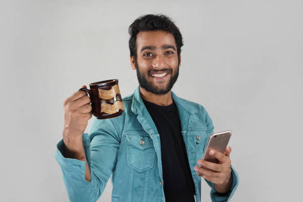 istock a man with a coffee cup and mobile watching news and smiling 1319769119