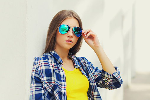 Portrait close up of beautiful young woman wearing a sunglasses posing in a city