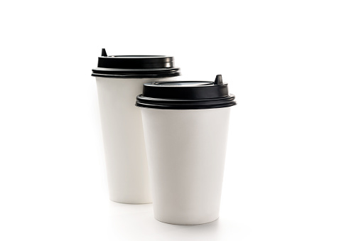 White paper cups for takeaway drinks on a white background with copy space. Two white coffee cups.