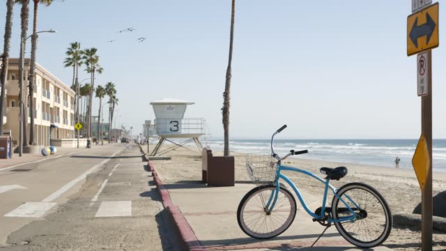 Bicycle cruiser bike by ocean beach, California coast USA. Summer cycle, lifeguard tower and palms.