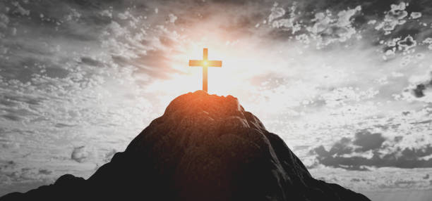 istock Cross on mountain peak at sunset christian religion 1319776024