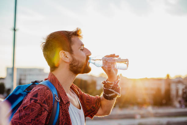 istock Young man is drinking water outdoors 1319778395