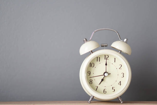istock Alarm clock on wooden table with grey background, selective 1319781477