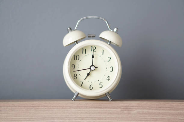 istock Alarm clock on wooden table with grey background, selective 1319781499