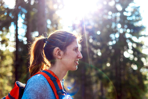 A young woman enjoying the hiking A young woman walking through the forest and enjoying nature.She has hearing aids and dental brace disabled person hiking outdoors stock pictures, royalty-free photos & images