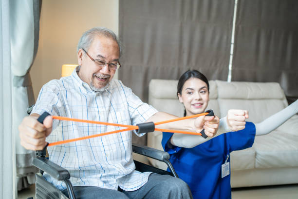 istock Asian Disabled senior elderly man on wheelchair doing physiotherapist with support from therapist nurse. Older handicapped man using resistance stretch band exercise for patient in home nursing care 1319783107