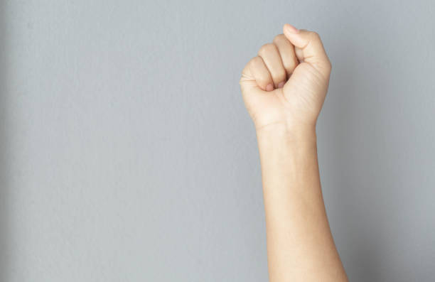istock woman hand with clenched fist on grey background 1319783692