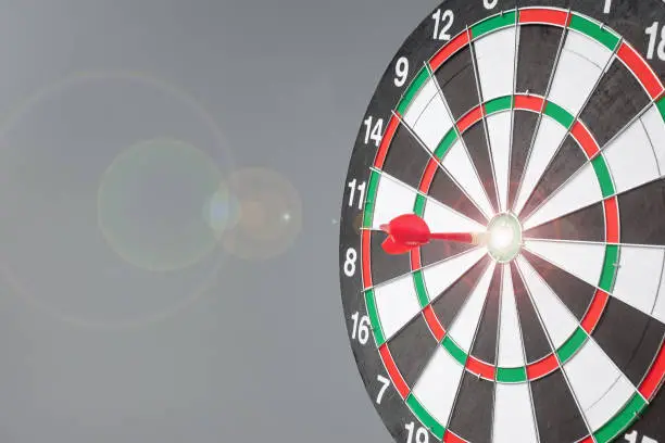 Photo of Red dart hitting a target on center of Bullseye or Dartboard. Business, competition, goal, success and marketing concept